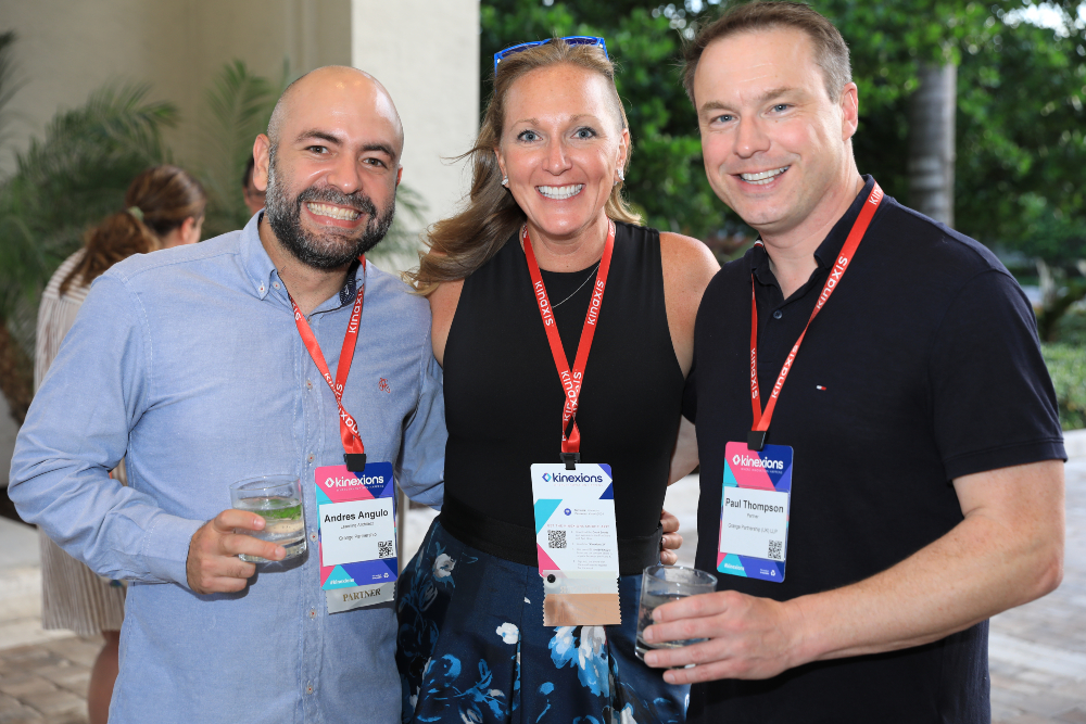 Three attendees at Kinexions smiling during an outdoor reception.