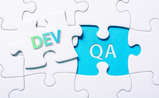 White puzzle pieces. One overlaid puzzle piece has the word "DEV" in green and blue letters. The letters "QA" appear in a blue space on the puzzle board.