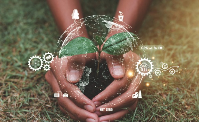 Stock photo of hands holding a small ball of soil with emerging plant sprout. Gear symbols surround the image with white graphics representing sustainable environmental energy green business goals.