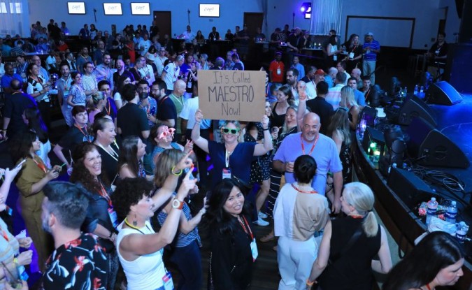 A woman holds up a handwritten sign reading "It's called Maestro now" in the crowd for the Flo Rida concert at Kinexions 2024.